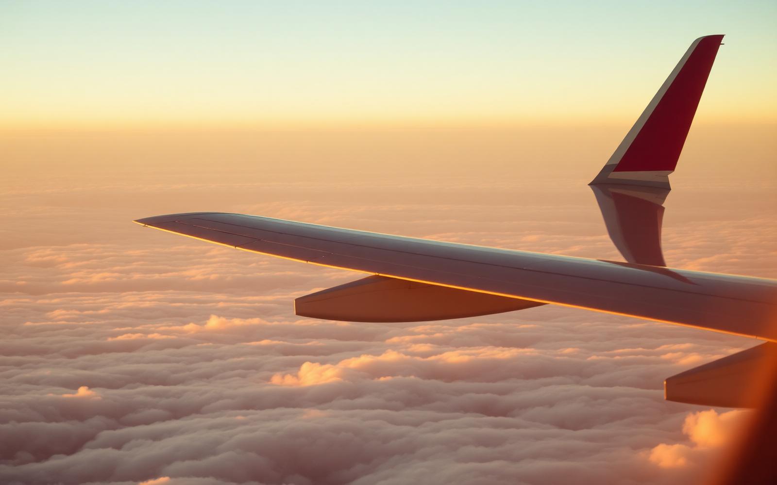 Aircraft wing above clouds at sunset
